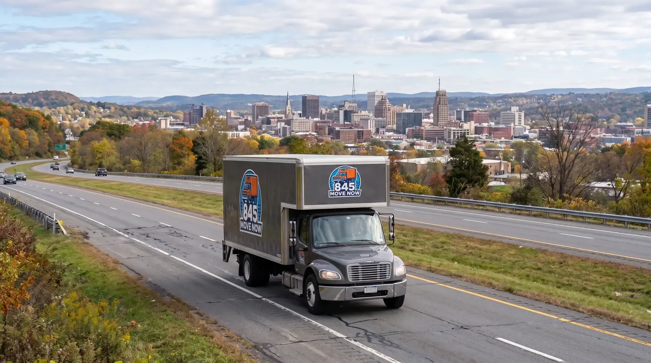 Moving truck on highway approaching downtown Syracuse in autumn