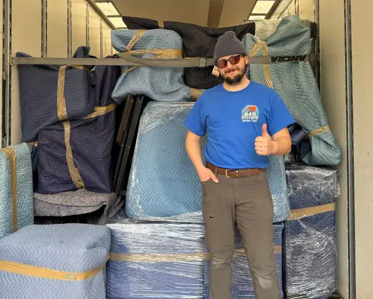Mover gives thumbs-up beside packed moving truck