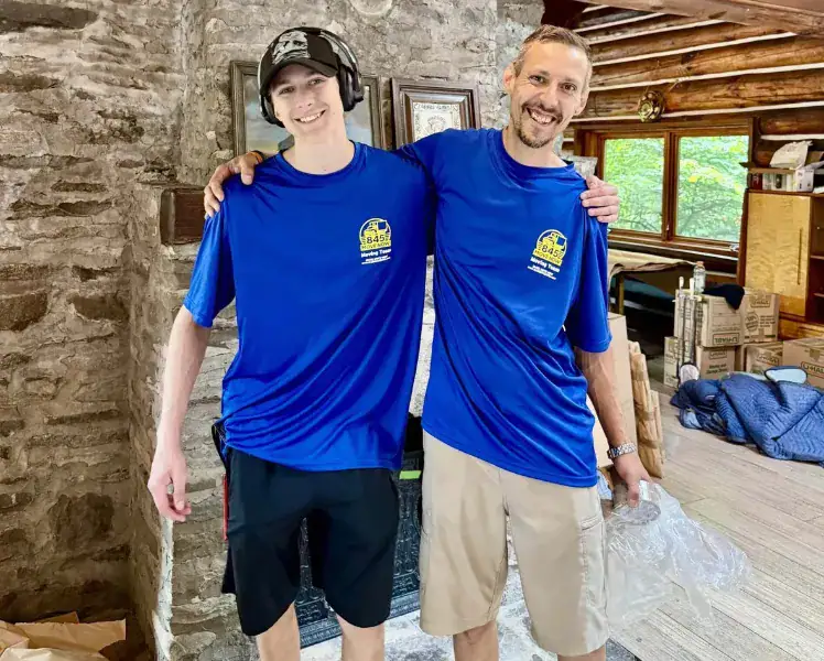 Two men in blue shirts smiling during a move