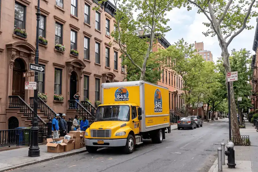 Expedited moving, a yellow 845 Move Now truck loading boxes on a brownstone street